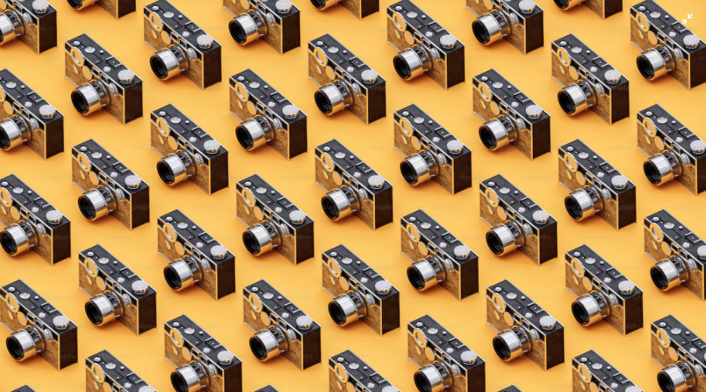 Photo of a series of retro cameras aligned on a yellow background
